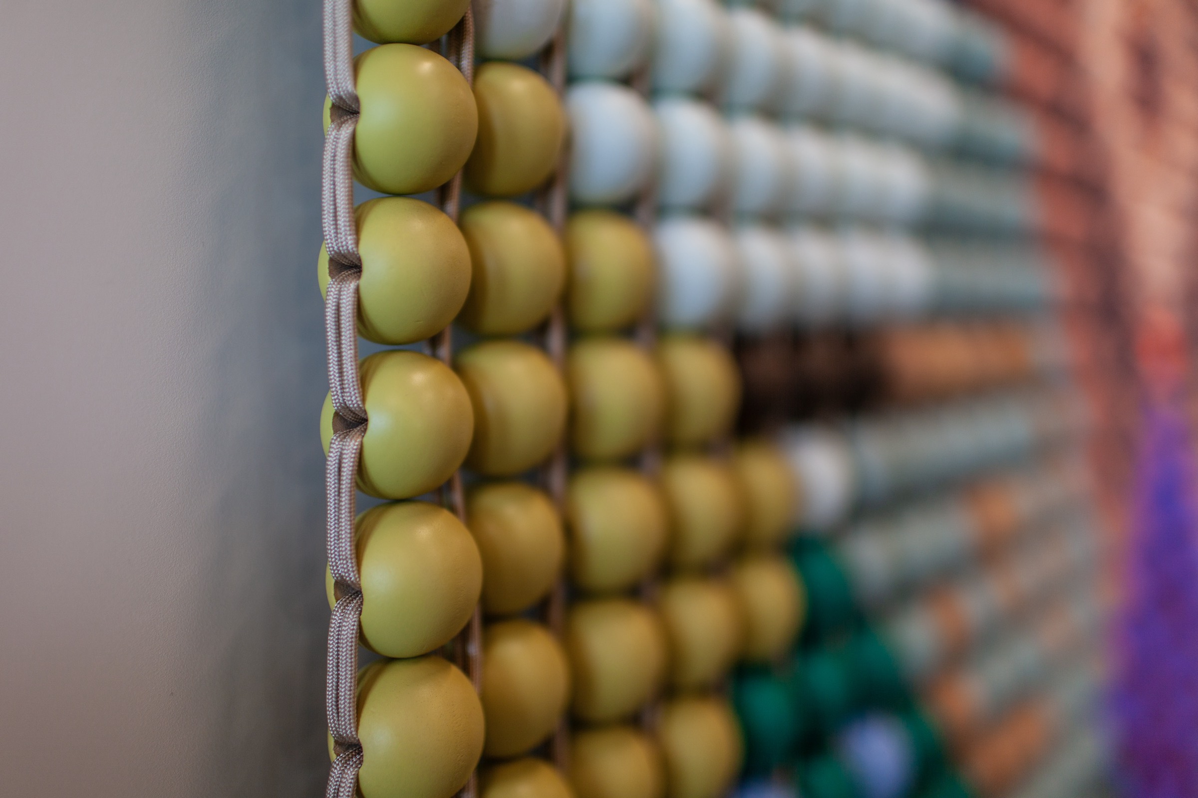 The edge of the beadwork: olive beads bound by cord, holding their shape without a frame